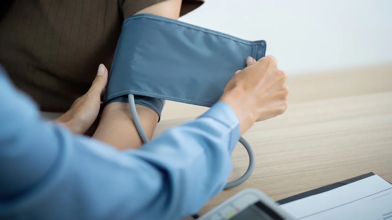 A blood pressure cuff being fitted around a patient's upper arm